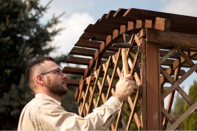 Tradesperson with a hammer repairing a pergola